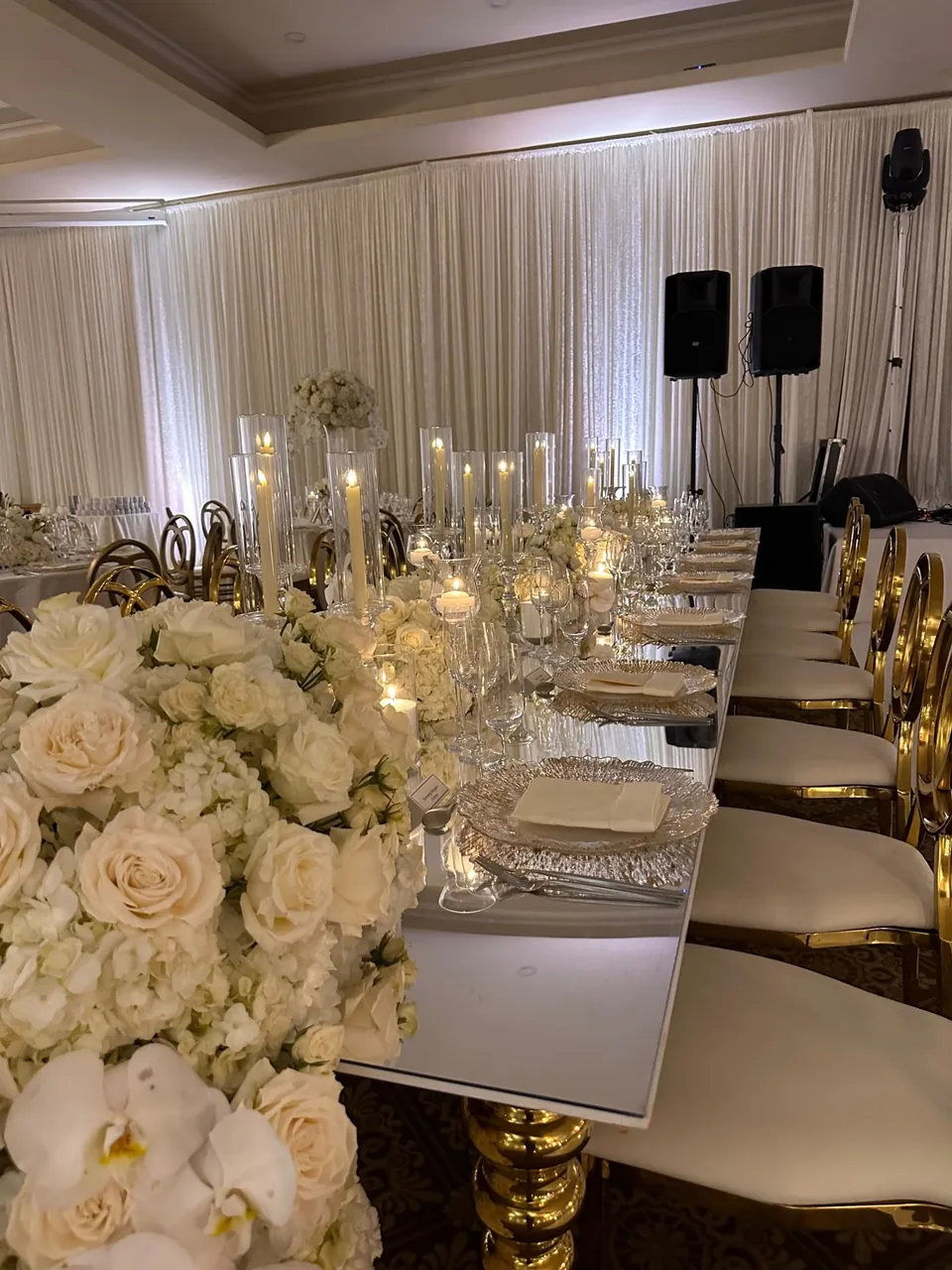 Long table with white orchids and candles in a draped ballroom