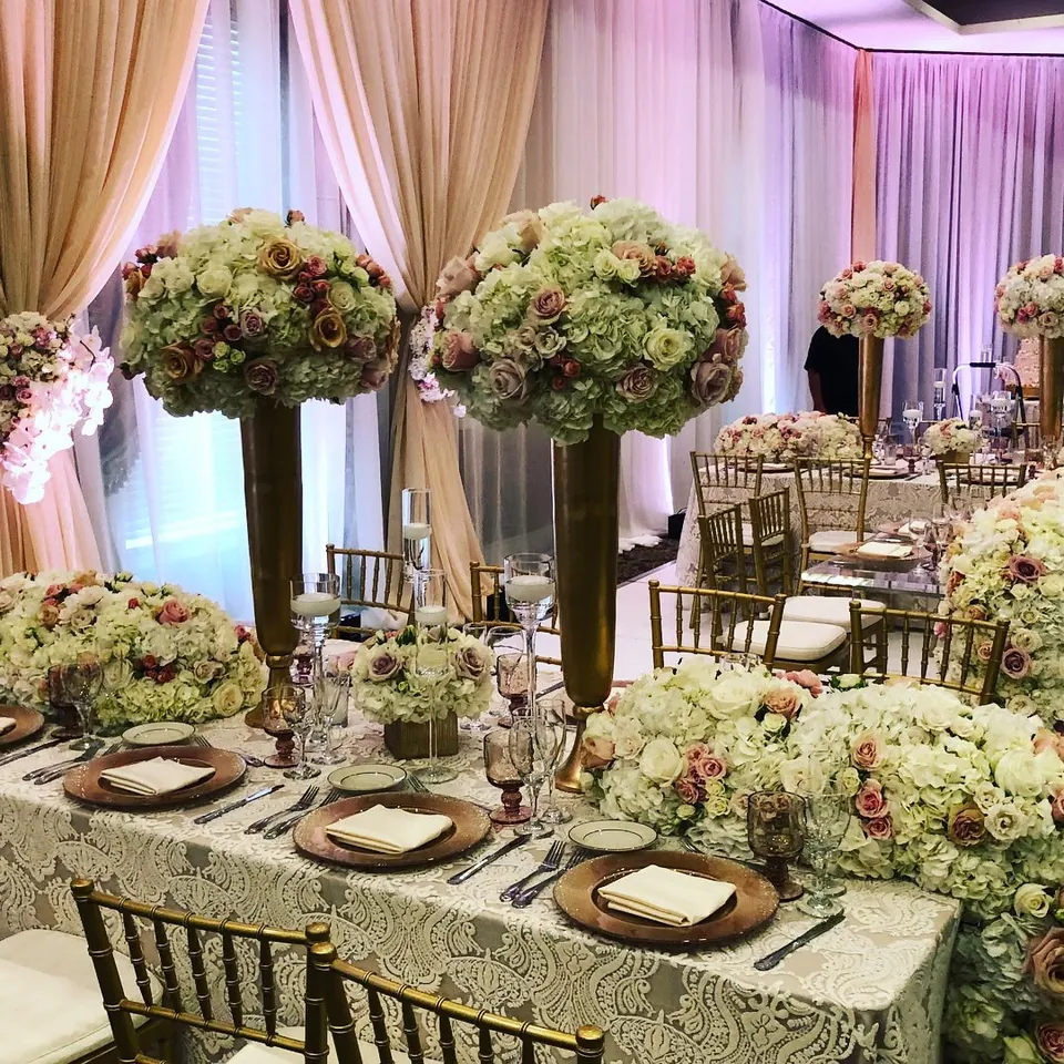 Gold chiavari chairs and tall pink and white floral arrangements in a ballroom