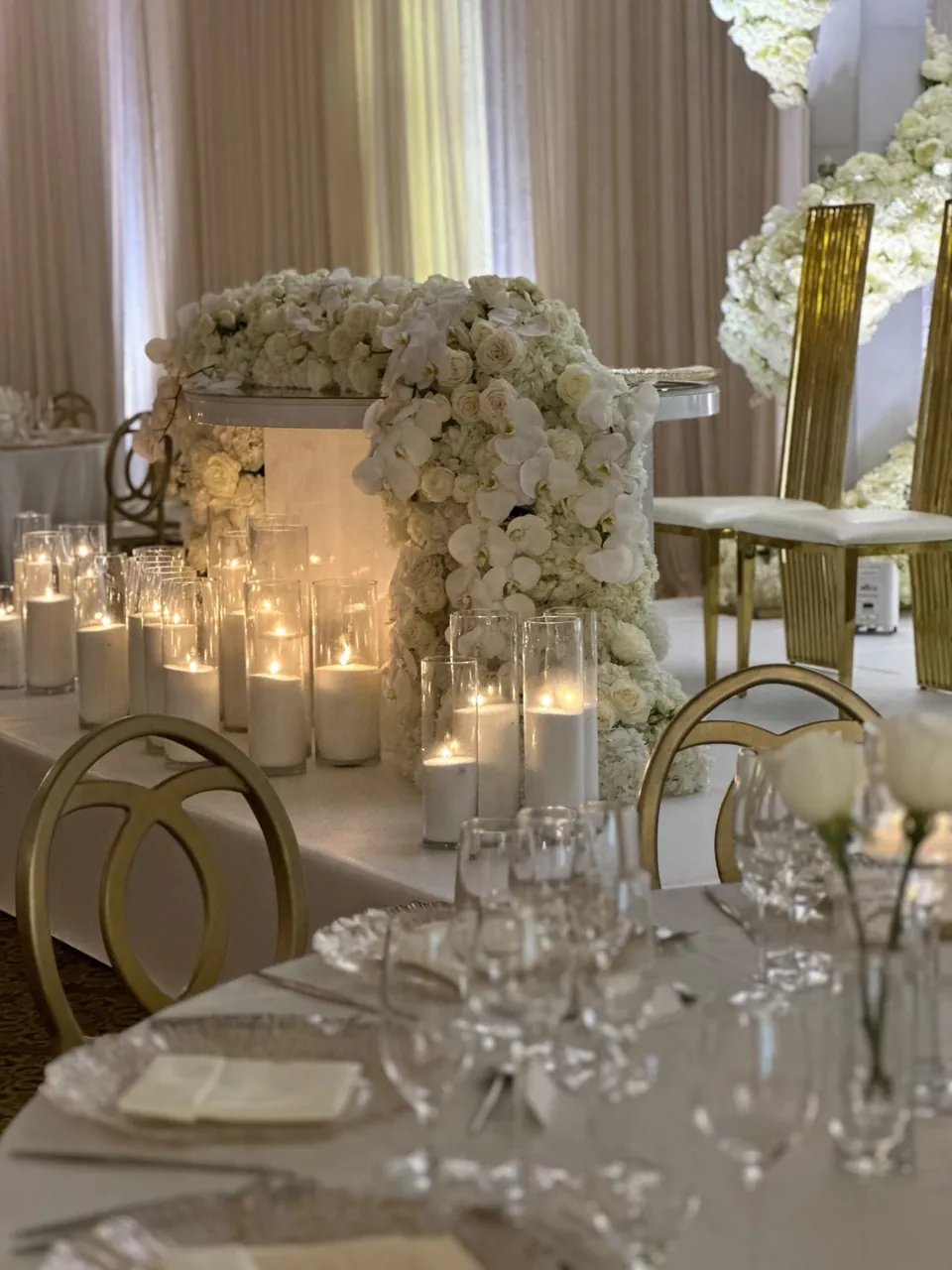 White floral centrepiece with candles and a gold chair