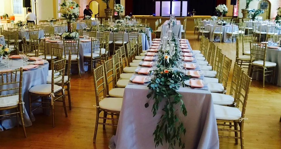 Long table with a green garland runner and gold chairs
