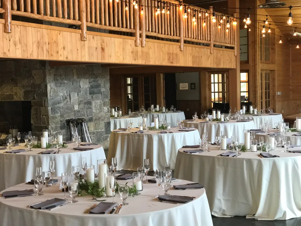 Round tables with white linen in a wood and stone hall