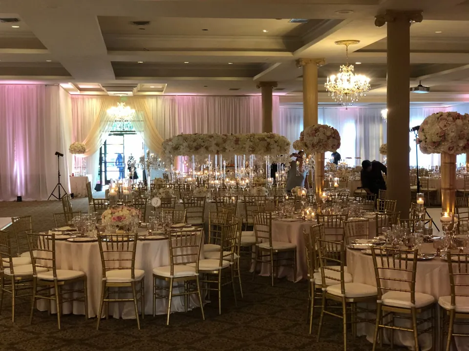 Ballroom set for a reception with draped walls and tall florals
