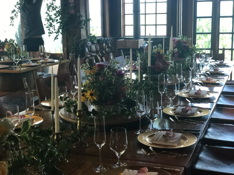 Long dark wood table with candles, greenery and gold chargers