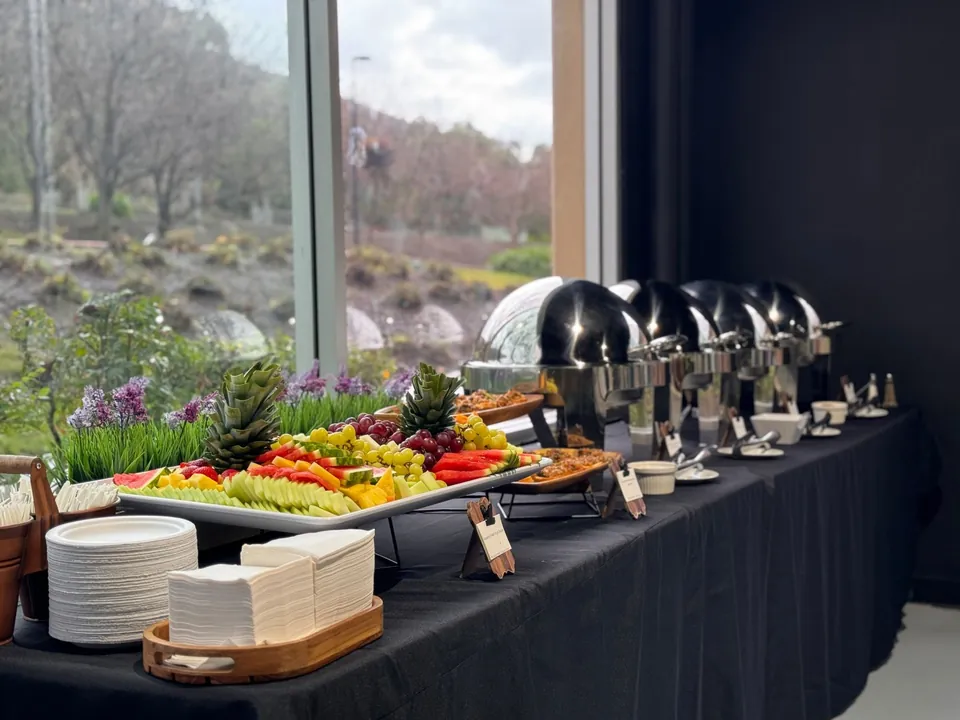 Buffet with chafing dishes and a fruit platter by a garden window