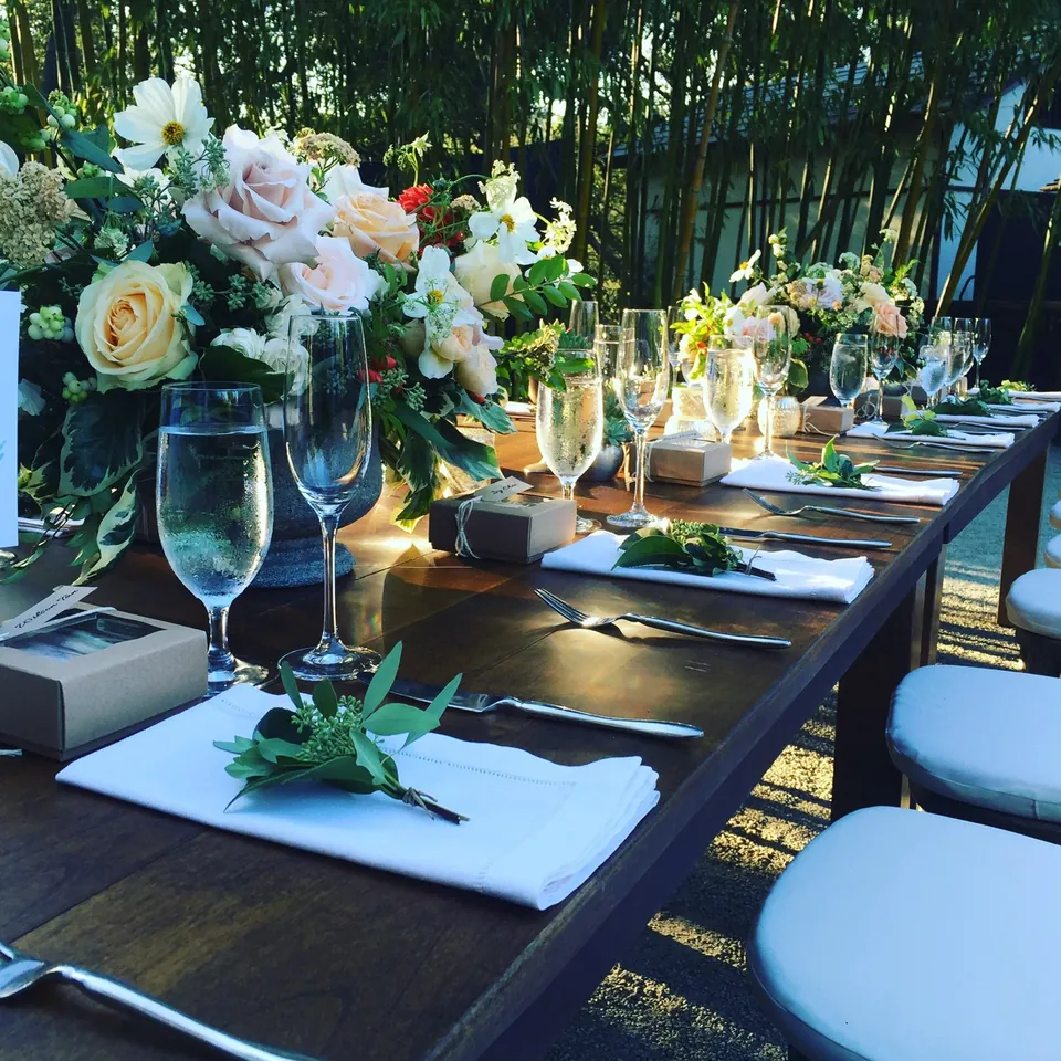 Wooden table setting with roses, glassware and sprigs of greenery