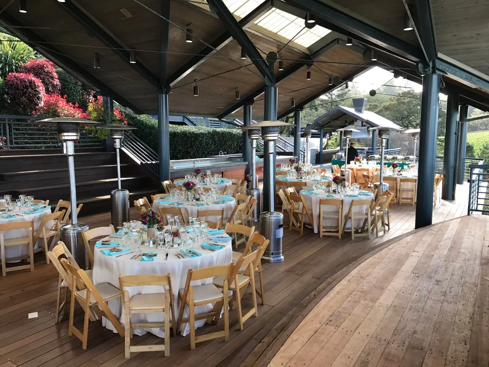 Round tables with turquoise napkins on a covered waterside terrace