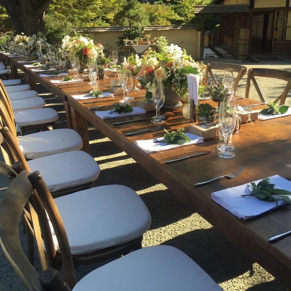 Long wooden table with crossback chairs and fresh flower centrepieces