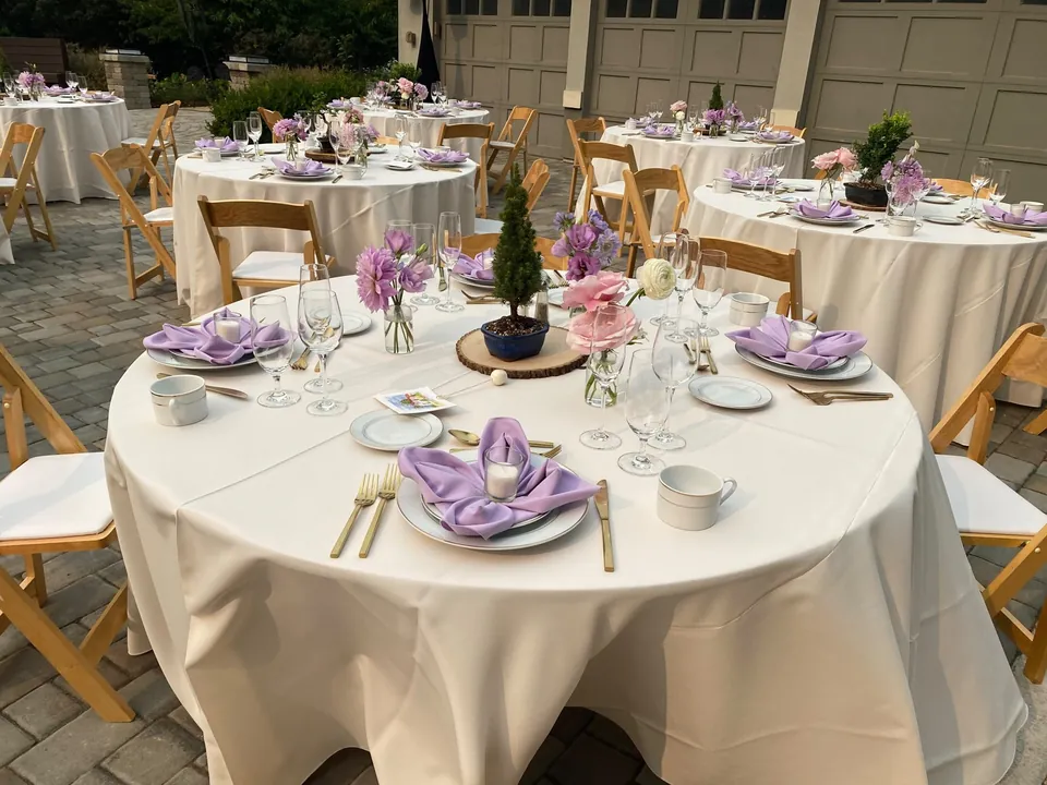 Round table in a courtyard with lavender napkins and a herb centrepiece